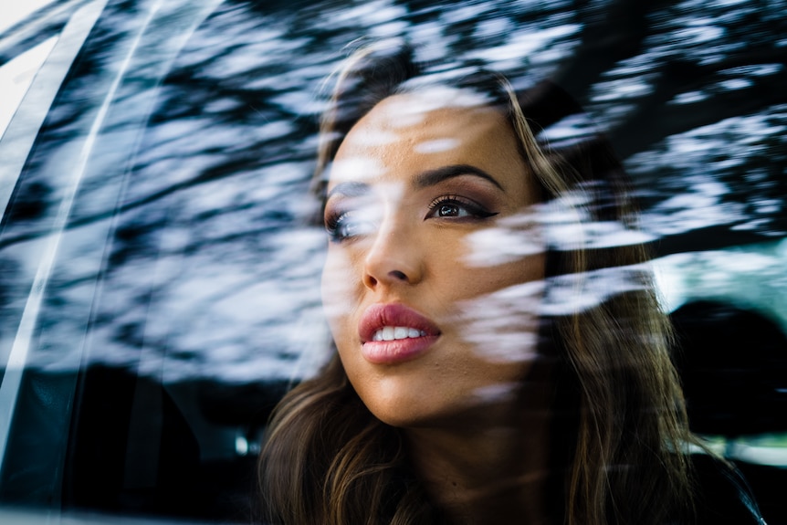 A woman looks out a car window.