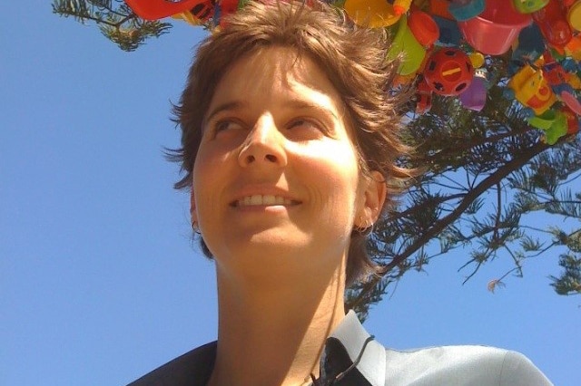 A smiling Mel Tregonning with a colourful art installation in the background.