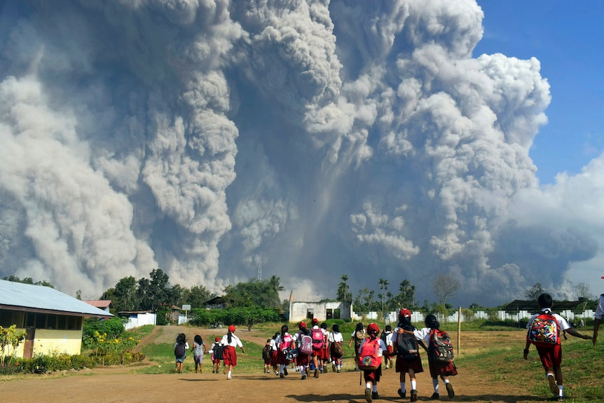 School children walk as Mount Sinabung erupts in Karo, Indonesia, on February 19, 2018.