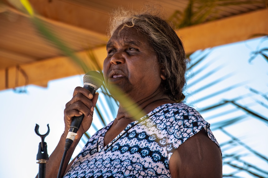 A woman is on stage talking into a microphone