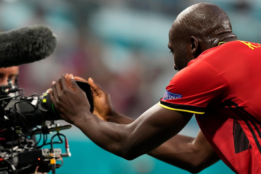 Romelu Lukaku se penche en avant et tient un appareil photo à deux mains