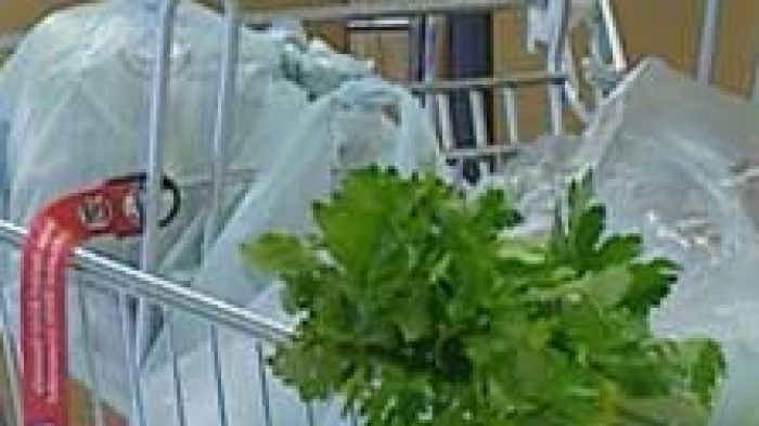 A supermarket shopping trolley filled with plastic bags