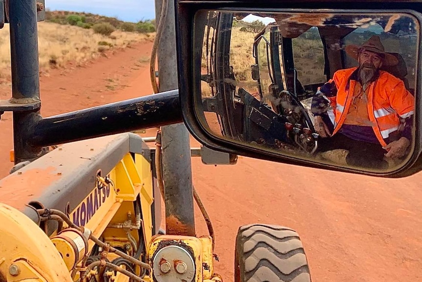 He is pictured in the rear-view mirror of his grader