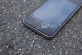 An iPhone lies on the ground with a cracked screen