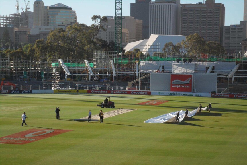 Get set... ground staff take the covers off this morning in preparation for play.