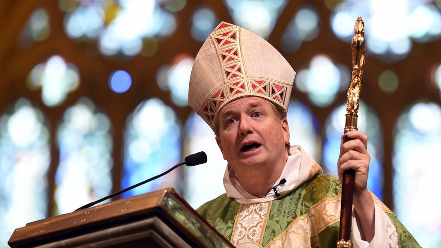 Fisher, decked out in clergy attire, presents a sermon.