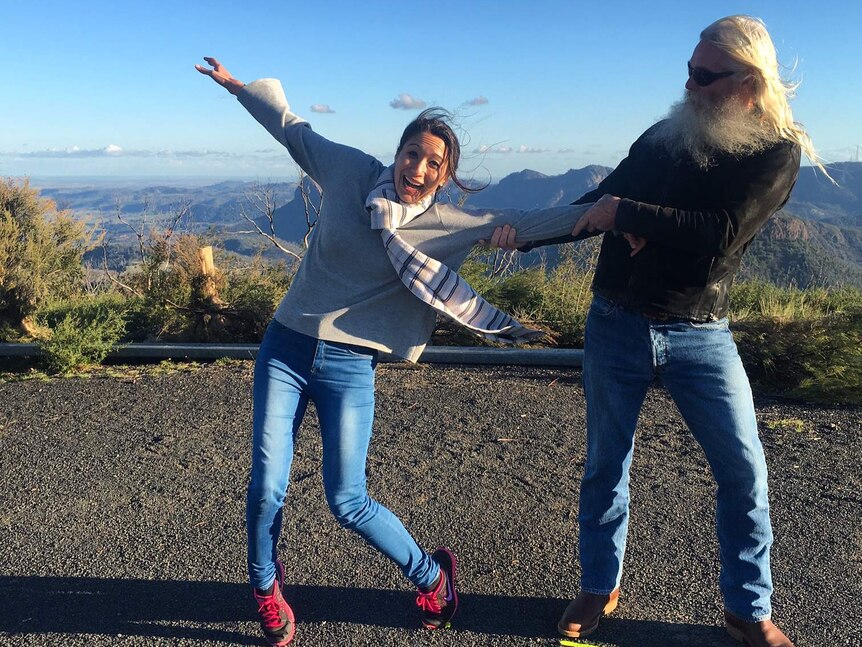 Bearded man holds woman by the arm on windy lookout