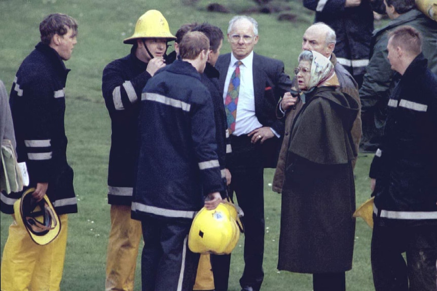 Queen Elizabeth II stands with firemen after a fire broke out at Windsor Castle.