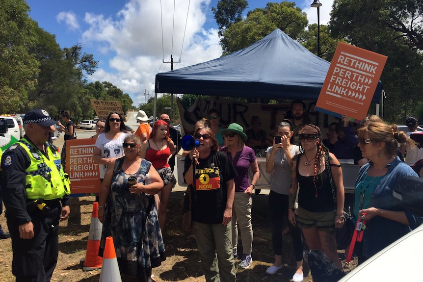 A crowd of protesters in front of a pop-up blue tent.