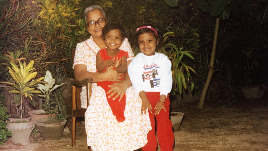 An old photo of a very young Dinalie posing for a picture with her sister and grandmother