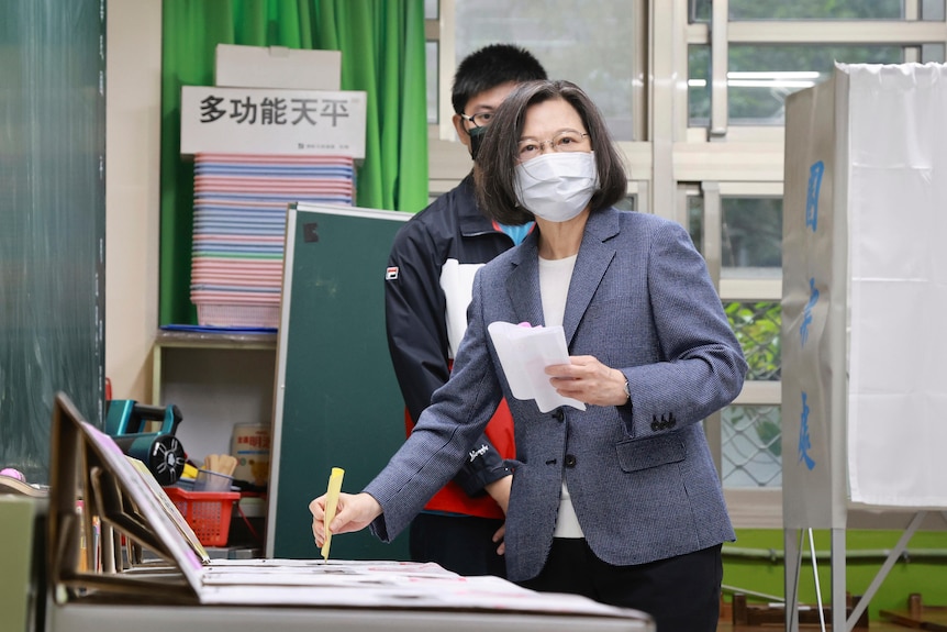 Masked President Tsai casts her ballots at a polling station.