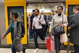 People alight from a busy train