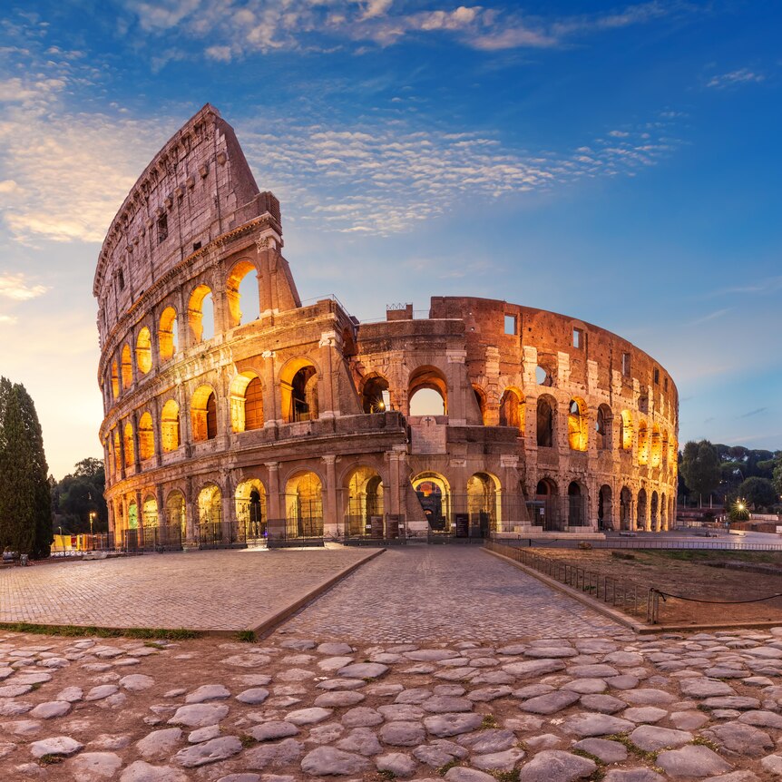 An image of the Roman Colosseum at sunrise, an amphitheatre made of stone, now partially ruined. 