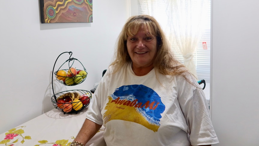 A woman with a smile, with Indigenous art in the background