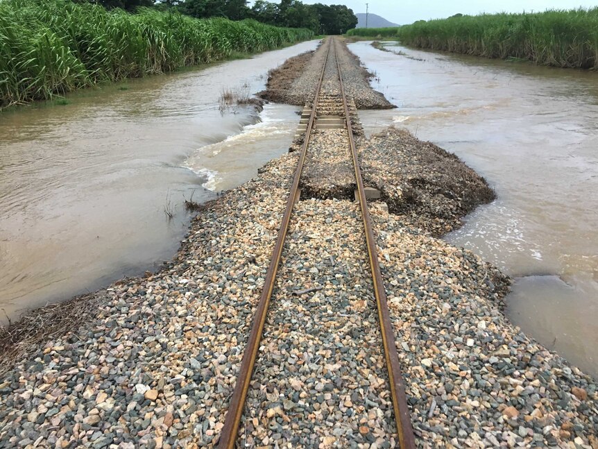 Cane train railway, with concrete slabs missing, surrounded by water.