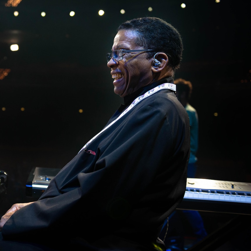 Herbie Hancock leaning back from the piano with a grin on his face.