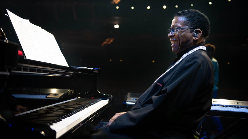 Herbie Hancock leaning back from the piano with a grin on his face.