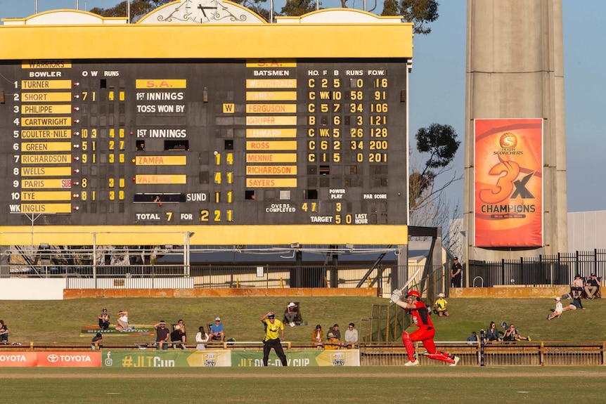 A wide shot from ground level of SA batsman Adam Zampa hitting a ball at the WACA Ground with the scoreboard in the background.