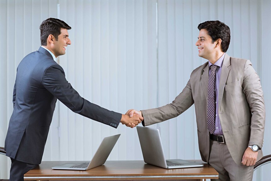 Two men shake hands in boardroom