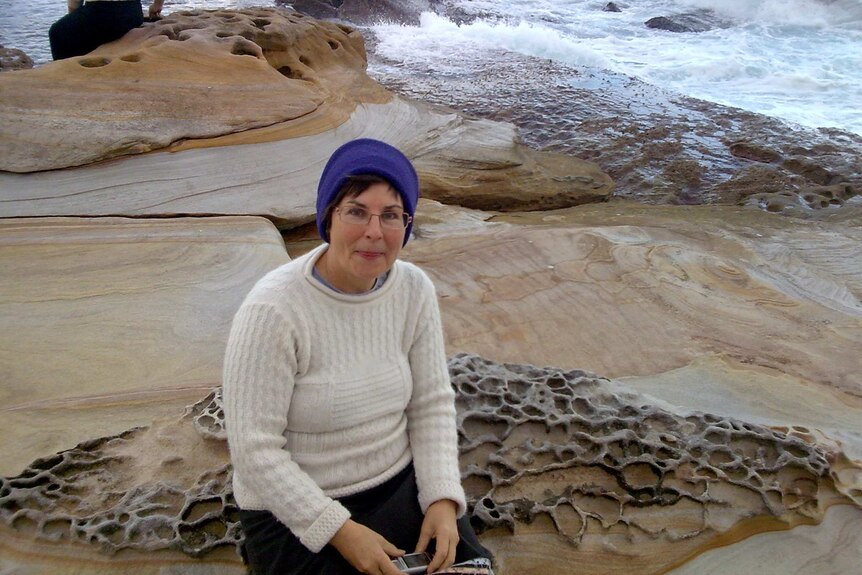 Judith McIntyre sitting on a rock at the beach.