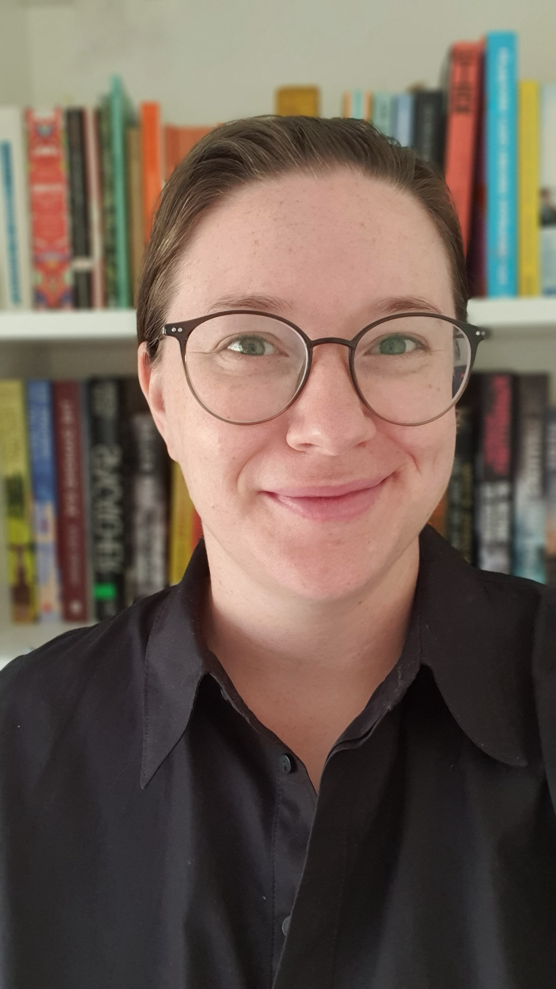 A lady with glasses smiling at the camera