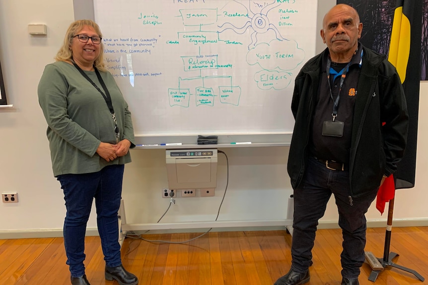Two people stand in front of a white board with writing exploring Treaty issues
