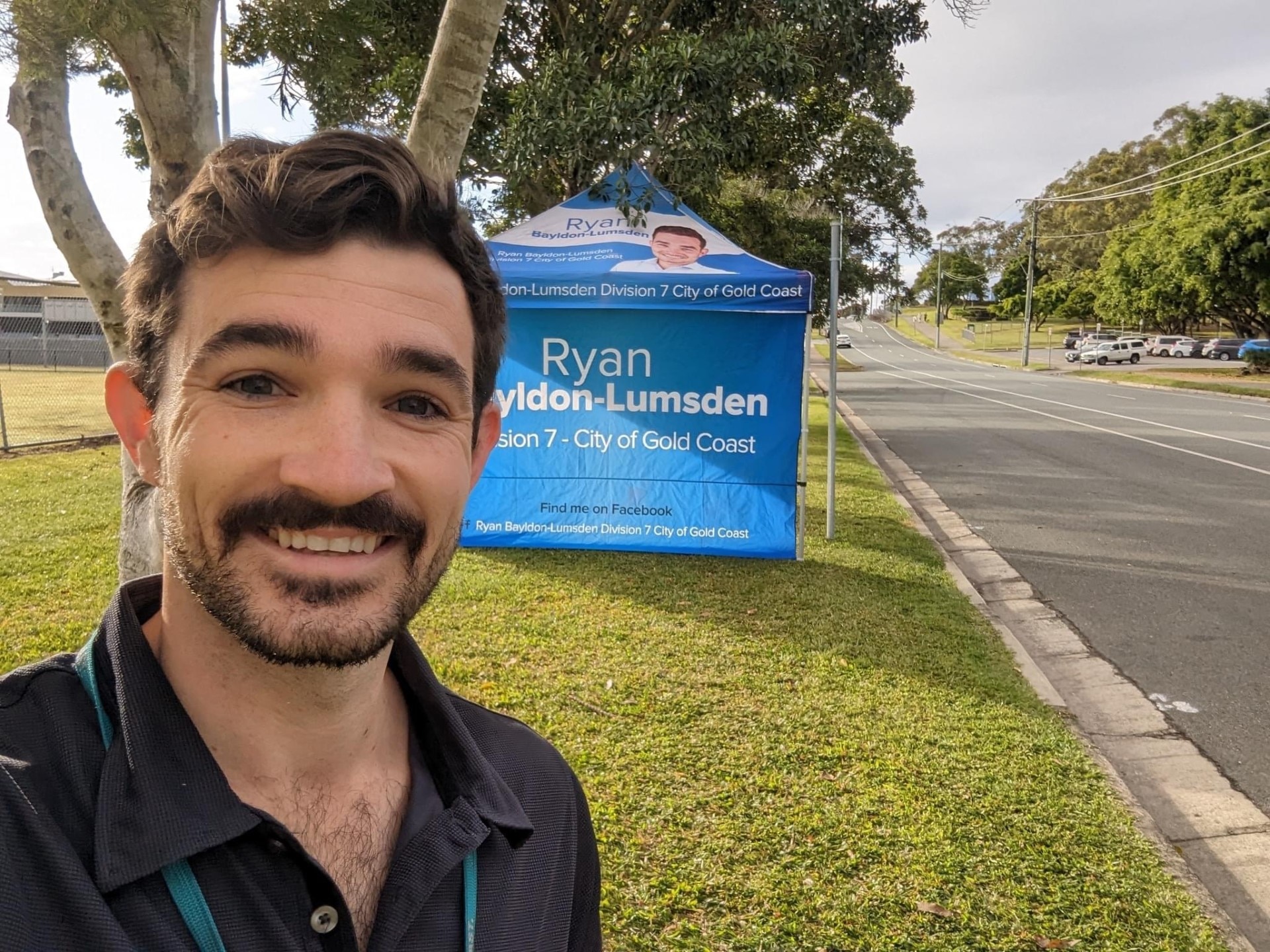 A man with a moustache in front of a party tent.