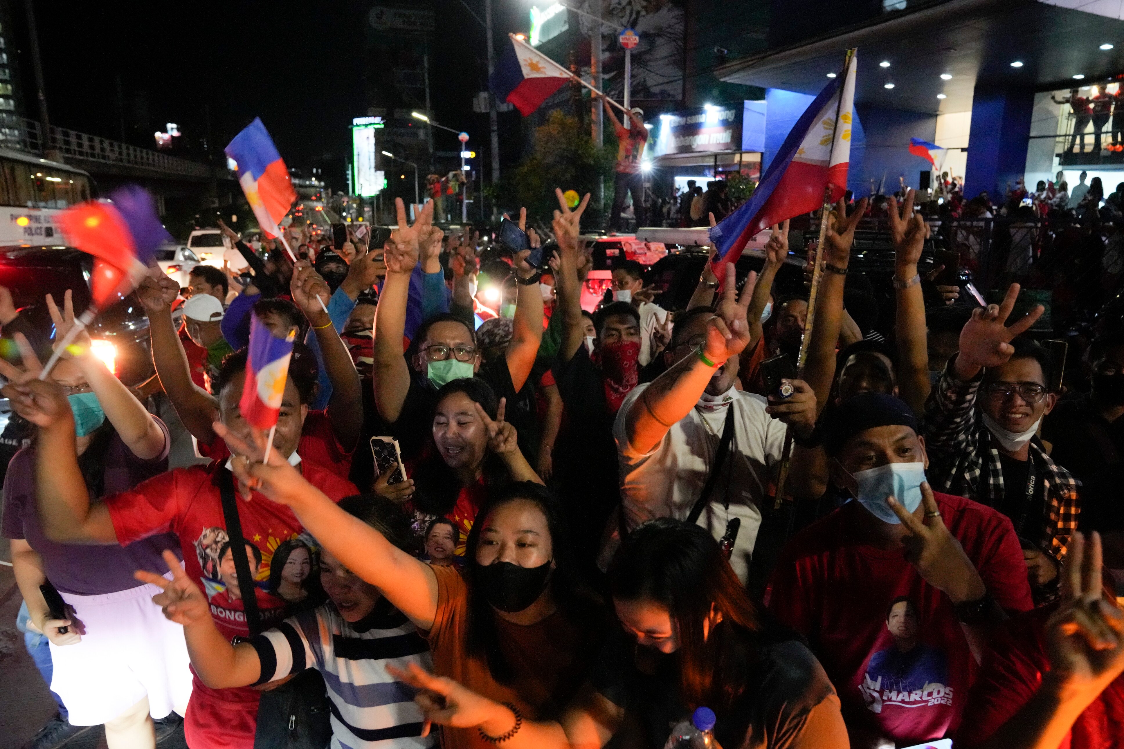 A crowd of people wave Filipino flags and cheer