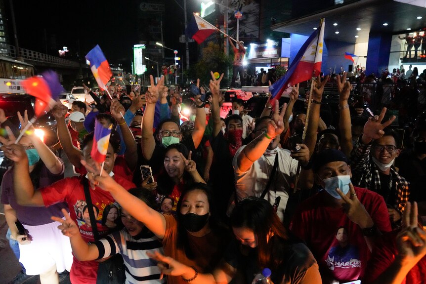 A crowd of people wave Filipino flags and cheer
