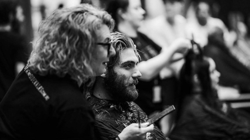 A volunteer hairdresser cuts the hair of someone experiencing disadvantage