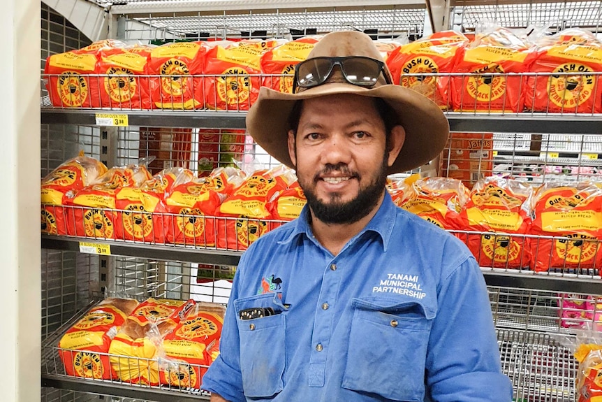 Chris Mandigalli stands in front of racks of bread in a supermarket.
