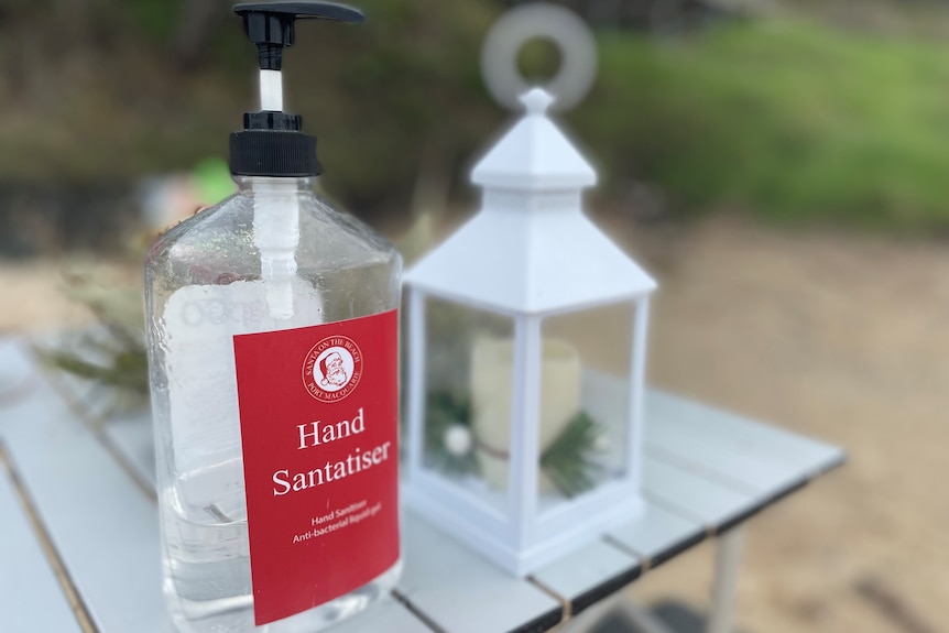 A bottle of hand sanitiser with the label 'Santatiser' sits on an outdoor table.