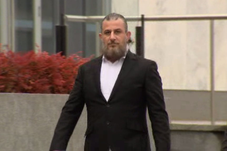 A man in a suit walkig out of court. 