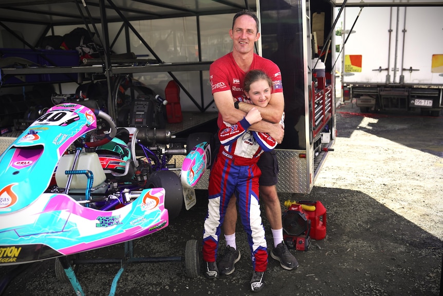 Adrian hugs Lana while they stand next to her blue and pink go kart.