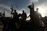 Fighters hold up their guns in Libya