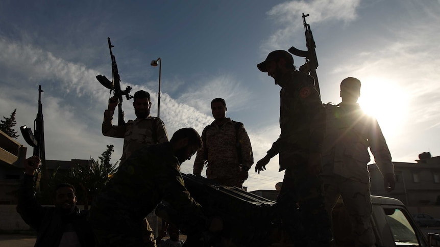 Fighters hold up their guns in Libya