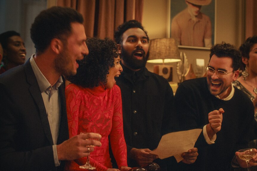 A film still of Jamael Westman, Himesh Patel, Ruth Negga and Daniel Levy, standing together laughing and singing.