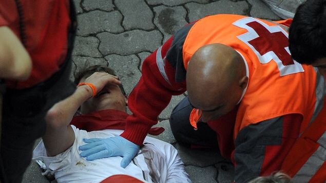 An unidentified Melbourne man gets medical care after been injured on the bull run.