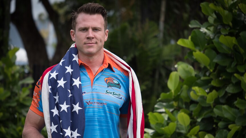 Man in Northern Pride rugby league club jersey standing with an American flag draped over his shoulders.
