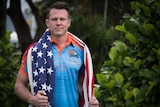 Man in Northern Pride rugby league club jersey standing with an American flag draped over his shoulders.