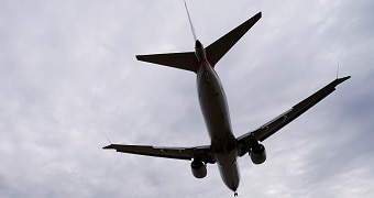 A plane photographed from underneath and silhouetted against clouds in the sky