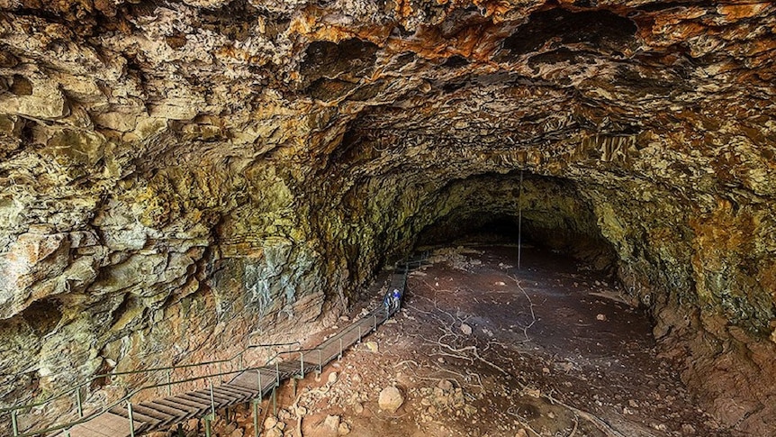 Tourists trek through a cave-like Undara lava tube