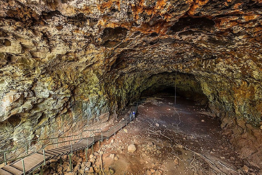 Tourists trek through a cave-like Undara lava tube