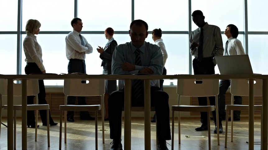 Silhouettes of office workers sitting and standing beside a desk and window.