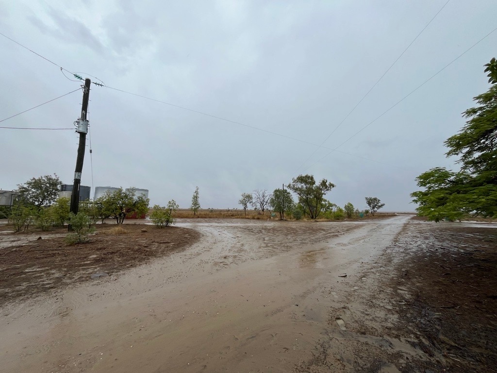 Un cielo gris rodea un camino embarrado que conduce a una propiedad en el oeste de Queensland