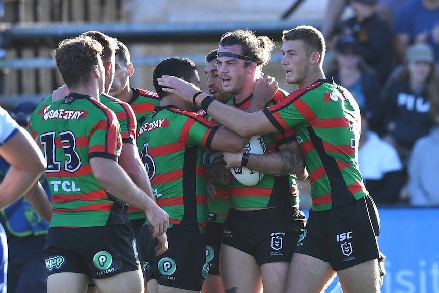 A huddle of players celebrate a try during a rugby league match