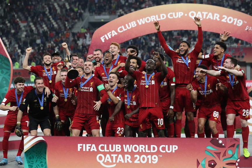 Soccer players jump up and down on a stage with the trophy after winning the Club World Cup.