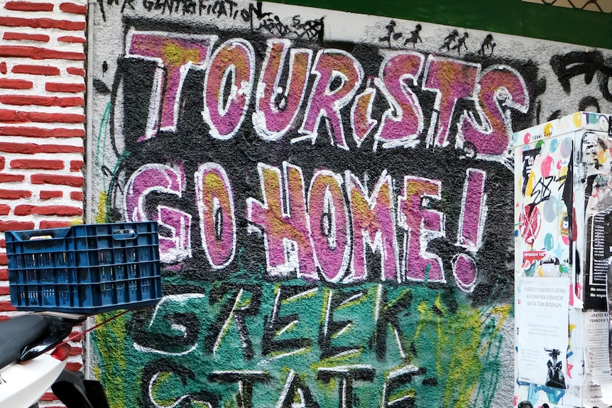 Graffitti on a wall in Athens saying "Tourists Go Home, Greek State Kills".