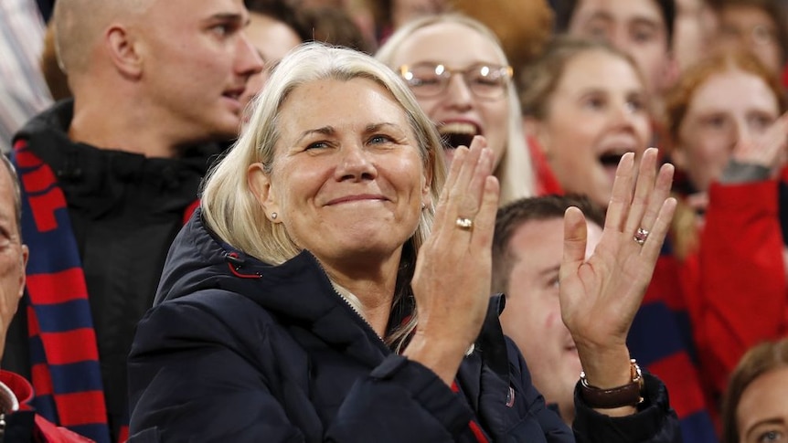 A photo of Kate Roffey smiling in the crowd, about to clap.