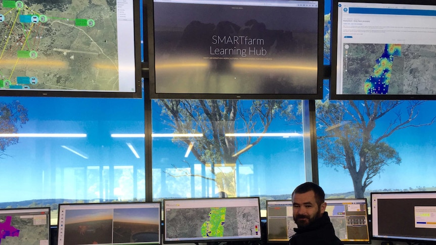 Senior lecturer Dr Mark Trotter looking at a series of computer screens that show data streaming from SMARTfarm paddocks